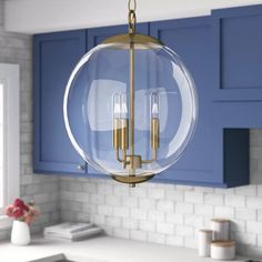 a kitchen with blue cabinets and a large glass globe light fixture hanging from the ceiling