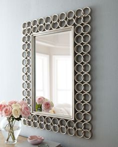 a mirror that is on the side of a wall next to a vase with flowers