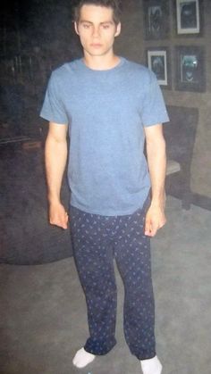 a man standing in front of a couch wearing blue pajamas and white shoes with his hands in his pockets