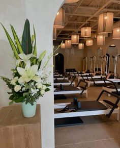 a room with rows of exercise equipment and flowers in a vase