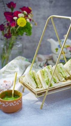 there is a tray with sandwiches on it and some dipping sauces in the bowl