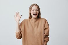 a woman is smiling and holding her hand up in the air while standing against a white background