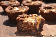 chocolate cupcakes with caramel drizzled on top sitting on a wooden surface