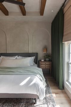 a bedroom with a large bed and green drapes on the window sill next to it