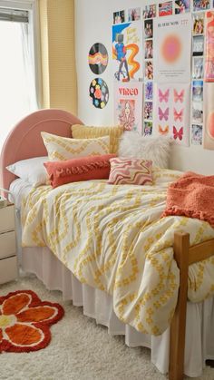 a bed with lots of pillows on top of it next to a wall full of pictures