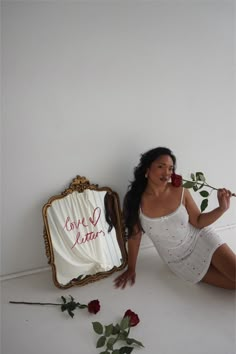 a woman sitting on the floor next to a mirror with roses in front of it