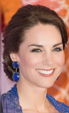 a smiling woman in blue dress with large earrings