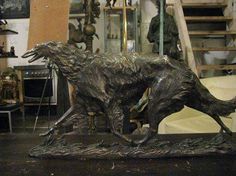 a bronze statue of a dog running in a room