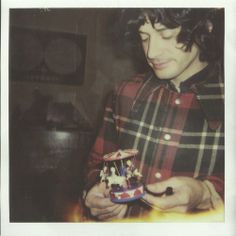 a young man is holding a toy in his hands and looking at the small figurine