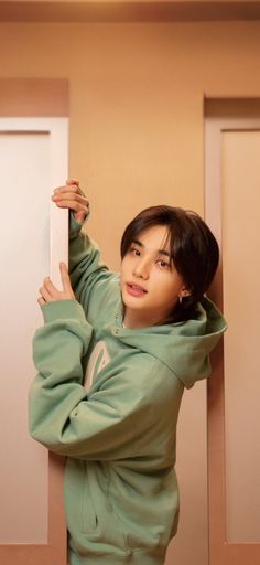 a person leaning against a wall wearing a green hoodie