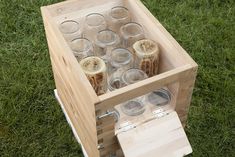 an open wooden box filled with glasses on top of green grass