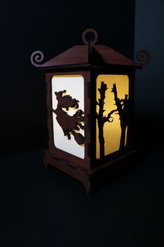 a lantern that is lit up with the silhouettes of trees and leaves on it