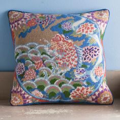 a decorative pillow on a shelf with blue walls in the background and an orange flowered design