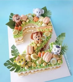 a cake shaped to look like the number one with animals and plants around it on a blue background