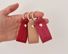 three leather keychains in the palm of a person's hand, with gold rings on them