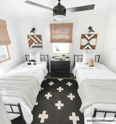 two twin beds in a small room with black and white rugs on the floor