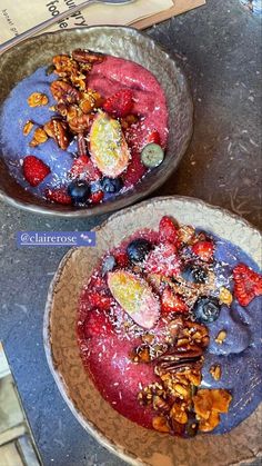 two bowls filled with fruit and granola sitting on top of a counter next to each other