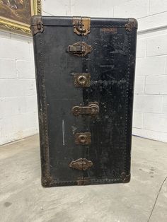 an old black suitcase sitting in front of a white brick wall