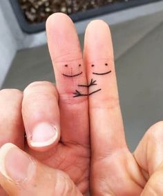 two fingers with faces drawn on them, one is holding the other's finger