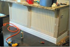 a kitchen counter with tools on the floor next to it