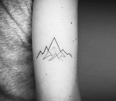 a black and white photo of a mountain tattoo on the right arm, with mountains in the background