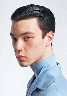 a young man with freckles on his face is looking at the camera while wearing a blue shirt