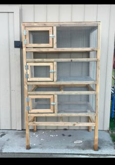 a wooden shelf filled with lots of caged items next to a garage door on the side of a building