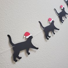 a black cat string with santa's hat on it and other cats hanging from the line