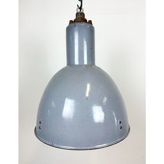 an industrial light hanging from the ceiling on a white wall with no one around it