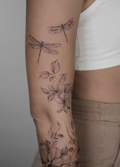 a woman's arm with flowers and dragonflys on the back of it