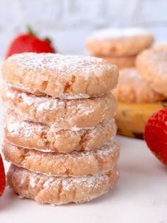 a stack of powdered sugar cookies next to some strawberries