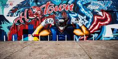 a large mural on the side of a building with a football player holding his hands up to his head