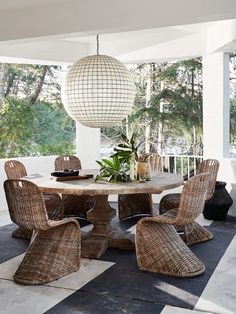 an outdoor dining area with wicker chairs and a round table on checkered tile flooring