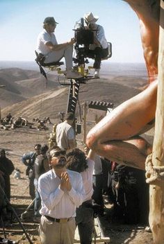 a group of people standing around each other in front of a cameraman on a tripod