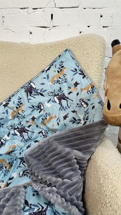 a stuffed animal sitting on top of a couch next to a blanket and pillow cover