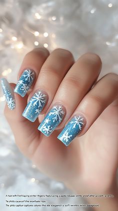 "A hand with five fingers displaying winter-themed nails featuring a pastel blue base, white snowflake accents, and icy silver glitter tips. The photo captures the elegance of the design against a soft, wintry background."