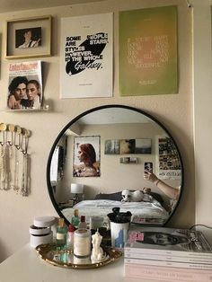 a mirror sitting on top of a table next to a wall with pictures and other items