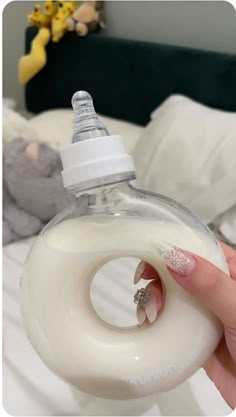 a woman's hand holding a baby bottle with a ring on the top and a diamond in the middle