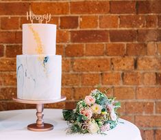 a white and blue cake sitting on top of a table next to a bouquet of flowers