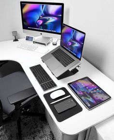 a white desk topped with two laptops next to a desktop computer and phone on top of it