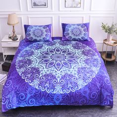 a bed with purple and white bedspread in a room next to a lamp