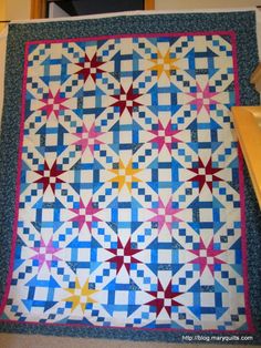 a blue and white quilt with red, yellow, and pink stars on the top