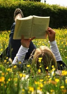 a person laying in the grass reading a book