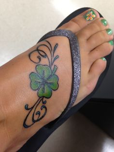 a woman's foot with a shamrock tattoo on it