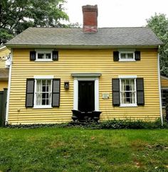 a small yellow house with black shutters