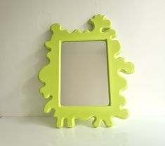 a green frame sitting on top of a white counter next to a wall mounted mirror