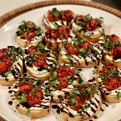 small appetizers with tomatoes, cheese and herbs are arranged on a white plate