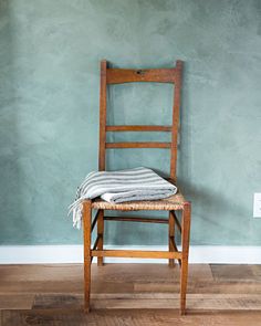 a wooden chair sitting in front of a blue wall