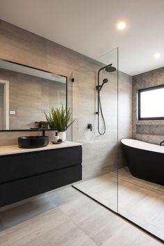 a bathroom with a black bathtub and a large mirror on the wall next to it