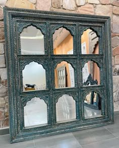 an old window with many mirrors on it's sides in front of a stone wall